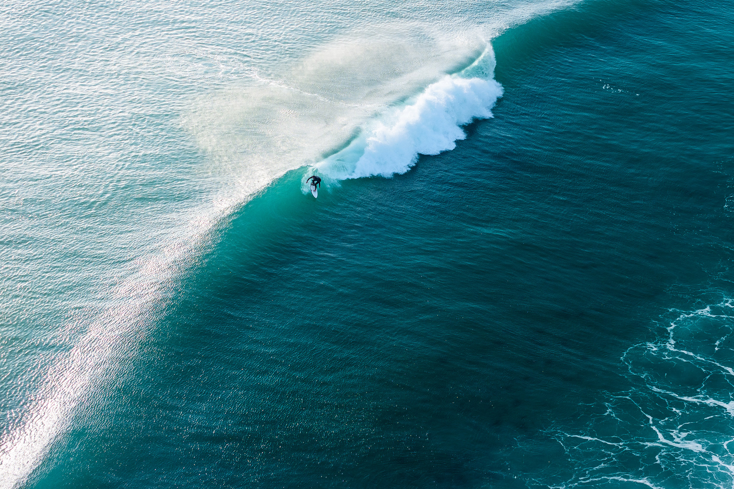 turquoise sea and foaming waves with small surfer in distance